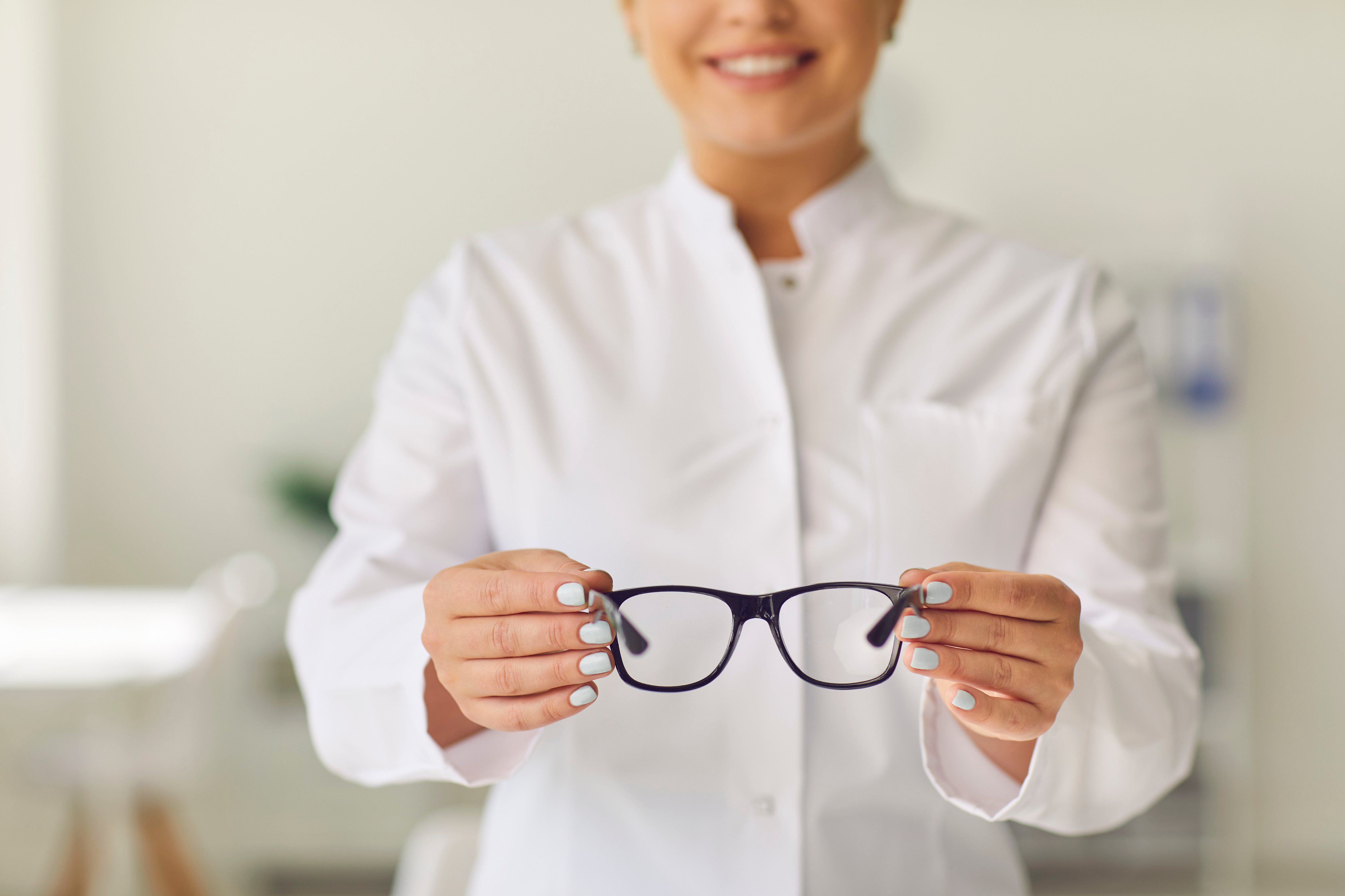 Professional Vision Specialist in a Clinic or Store Holding a Pair of Glasses with New Lenses.